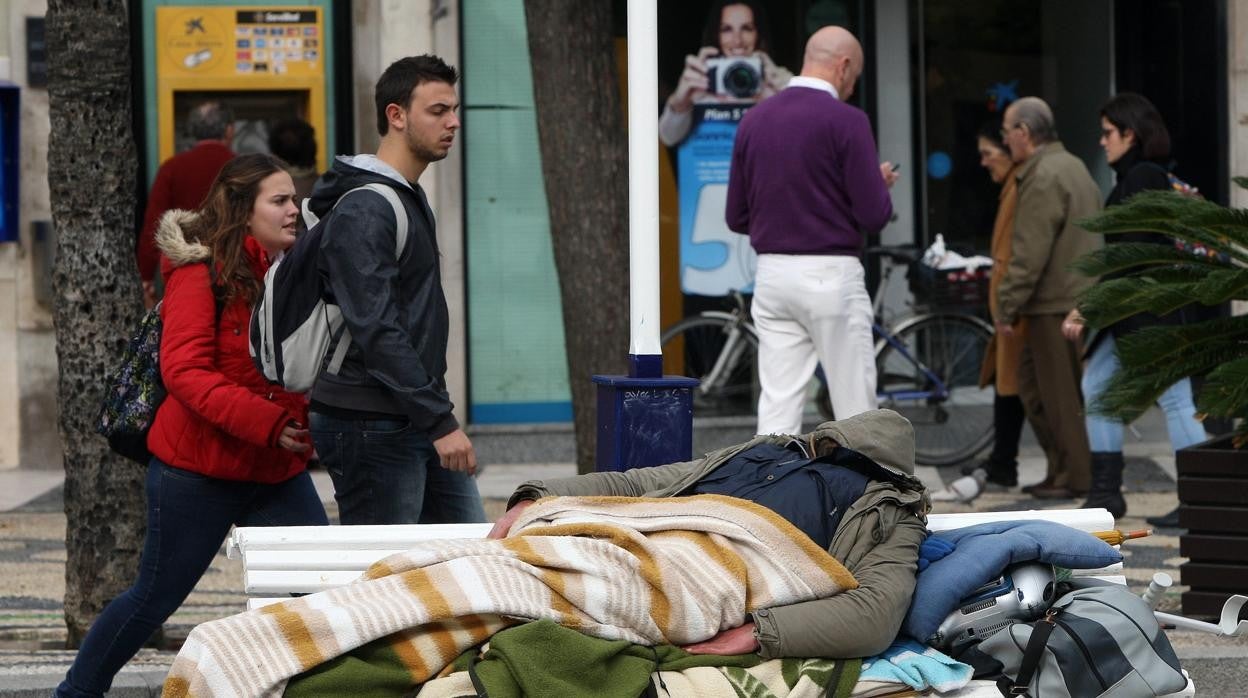 Una persona sin hogaar durmiendo en un banco de la capital.