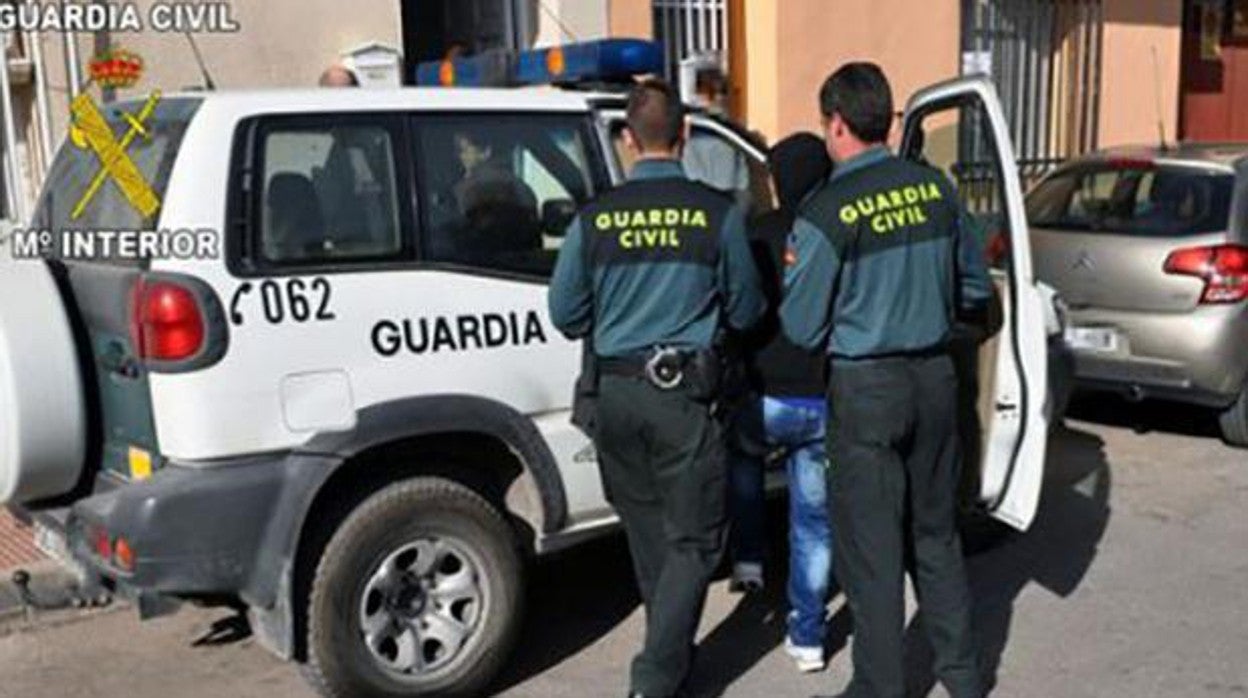 Dos agentes de la Guardia Civil introducen a un detenido en el coche en una actuación anterior