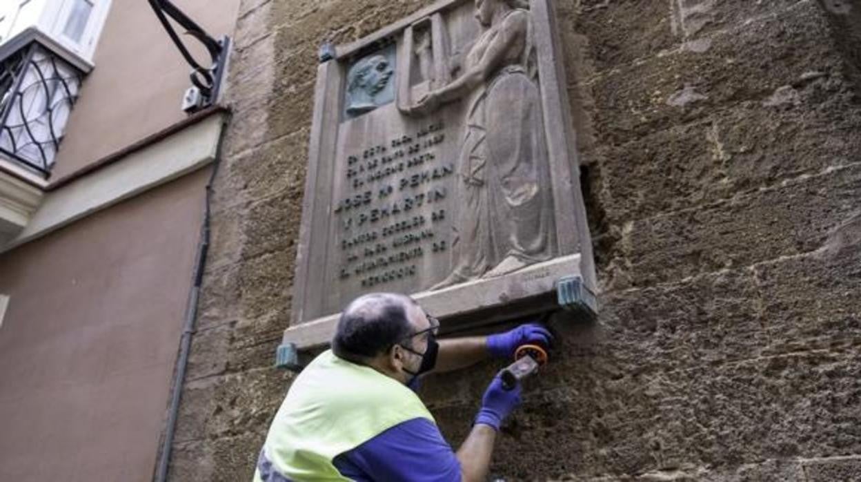 Un operario procede a la retirada de la placa en honor a José María Permán en su casa natal.