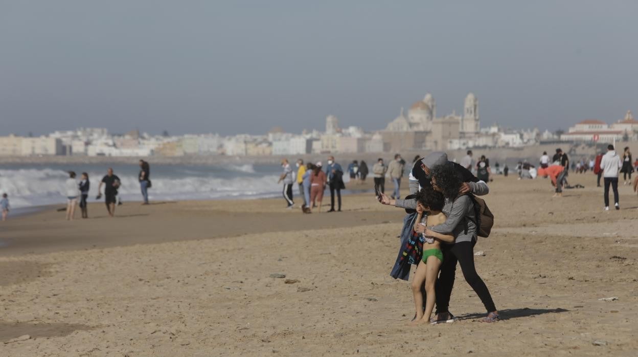 Una familia se hace un ‘selfie’ en la playa Victoria en el primer día del 2022.