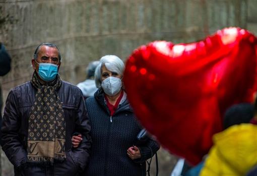 Una pareja con mascarillas en la calle.