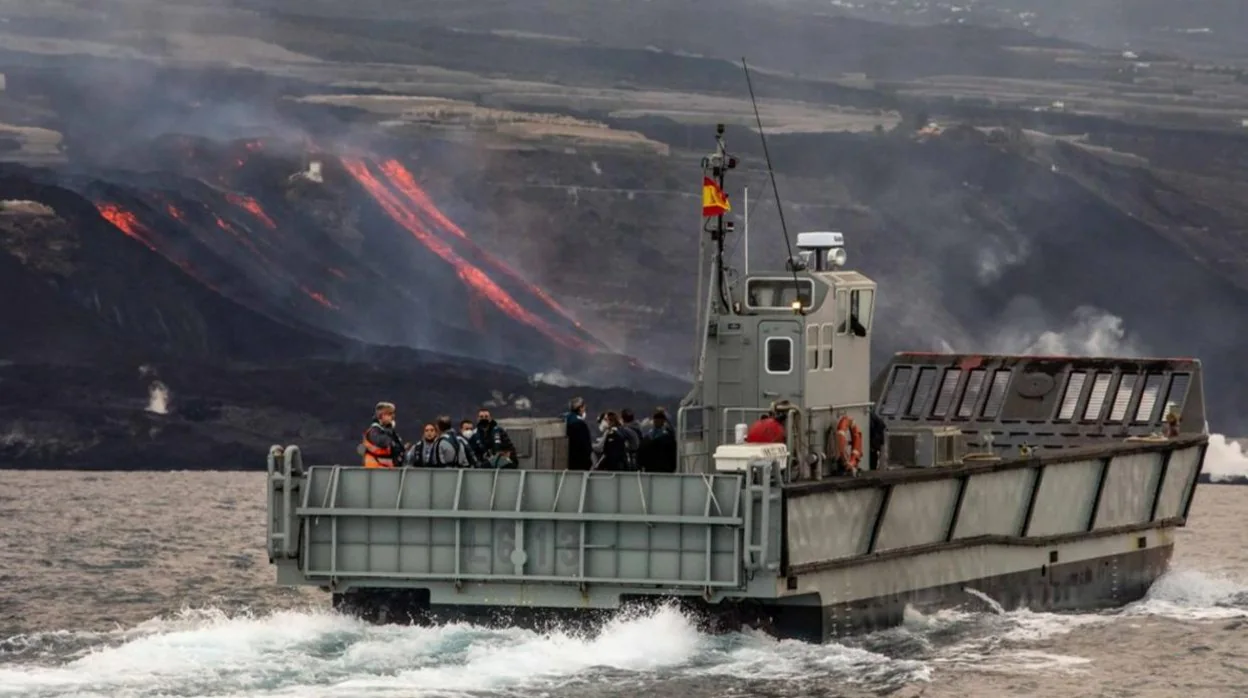 Una de las embarcaciones de transporte, con personal a bordo, con el volcán al fondo.