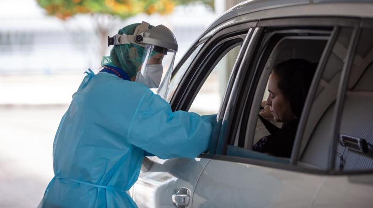 Una enfermera atiende a una conductora en Sevilla para practicarle una prueba PCR contra el Covid