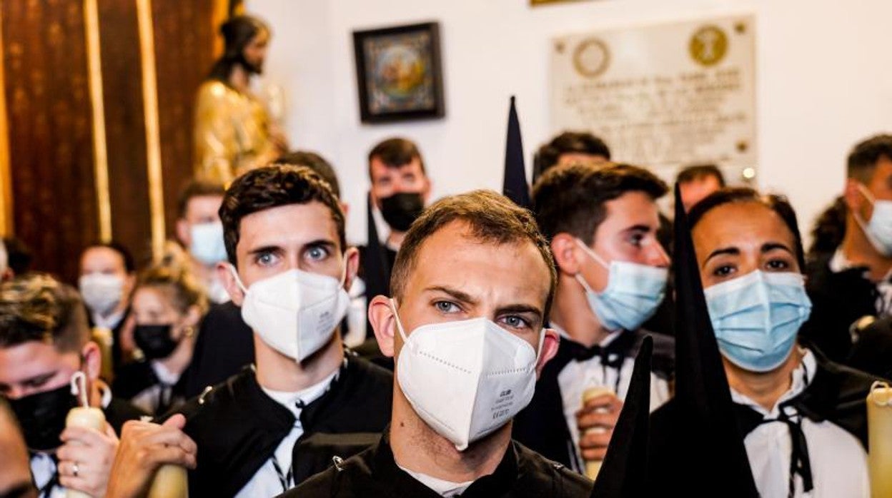 Varios nazarenos con mascarillas de la Hermandad de Santa Genoveva, en el interior del templo