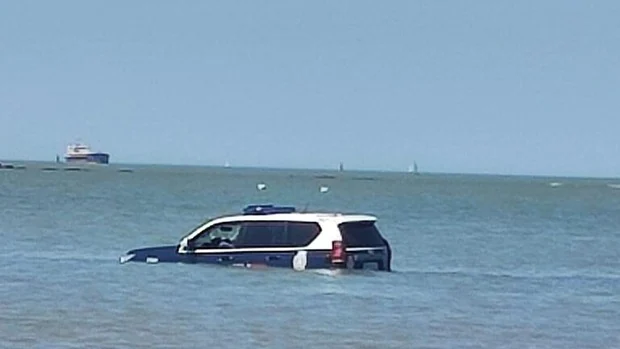 Un coche de la Policía Nacional encalla en la playa de Sanlúcar y acaba sumergido en el agua