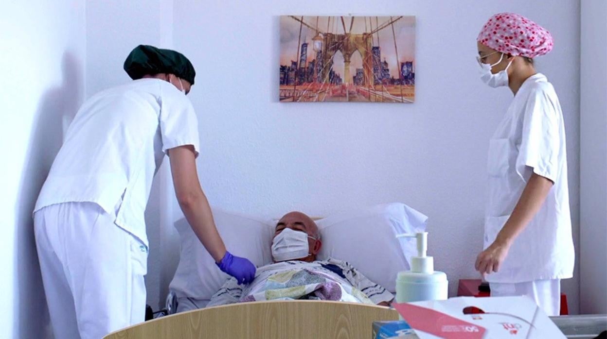 Foto de archivo: Dos trabajadoras de una residencia de mayores atienden a un usuario.