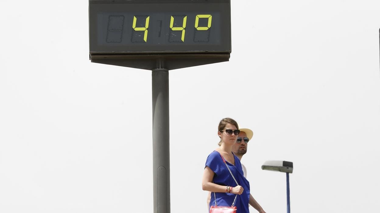 Dos personas pasan por delante de un termómetro que marca 44 grados