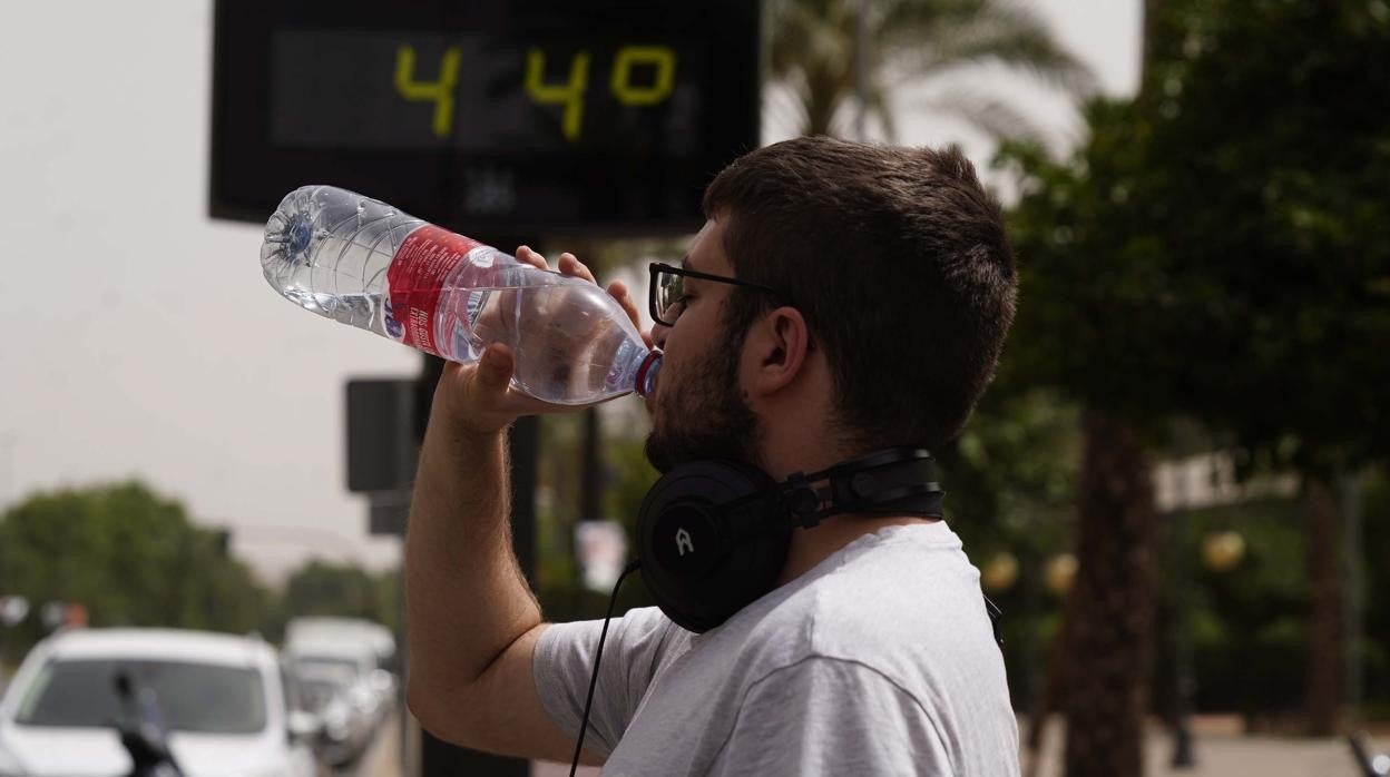 Un joven en Córdoba, frente al termómetro marcando los 44 grados