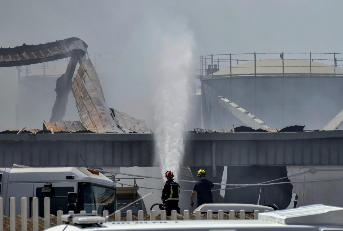 Una treintena de bomberos continúan refrescando los cascotes humeantes