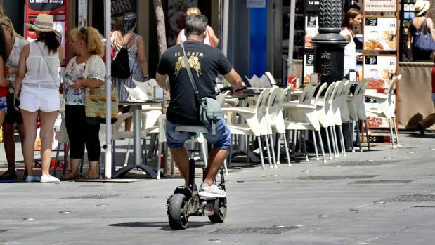 Usuario de un patinete eléctrico esta verano por el centro de Sevilla usando el carril bici