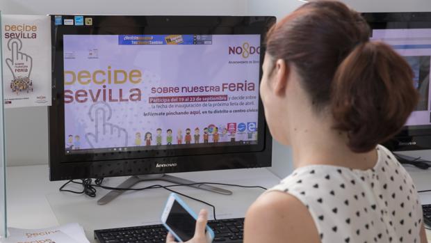 Una empleada municipal ante la web abierta «Decide Sevilla» para votar de forma telemática sobre la Feria de Abril