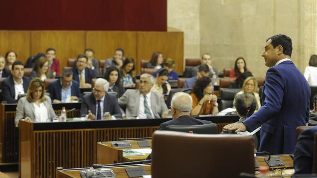 El portavoz del PP andaluz, Juanma Moreno, en primer plano y al fondo el Gobienro andaluz, en el Parlamento