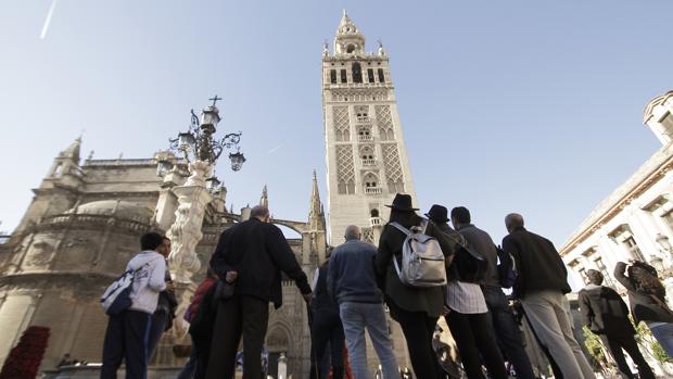 Turistas admiran la Giralda desde la plaza Virgen de los Reyes