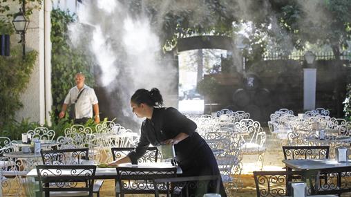 Una empleada prepara una mesa en una terraza