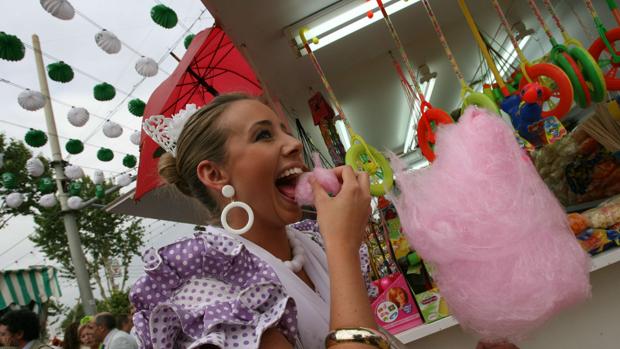 Una flamenca degusta una nube de algodón en el real de la Feria