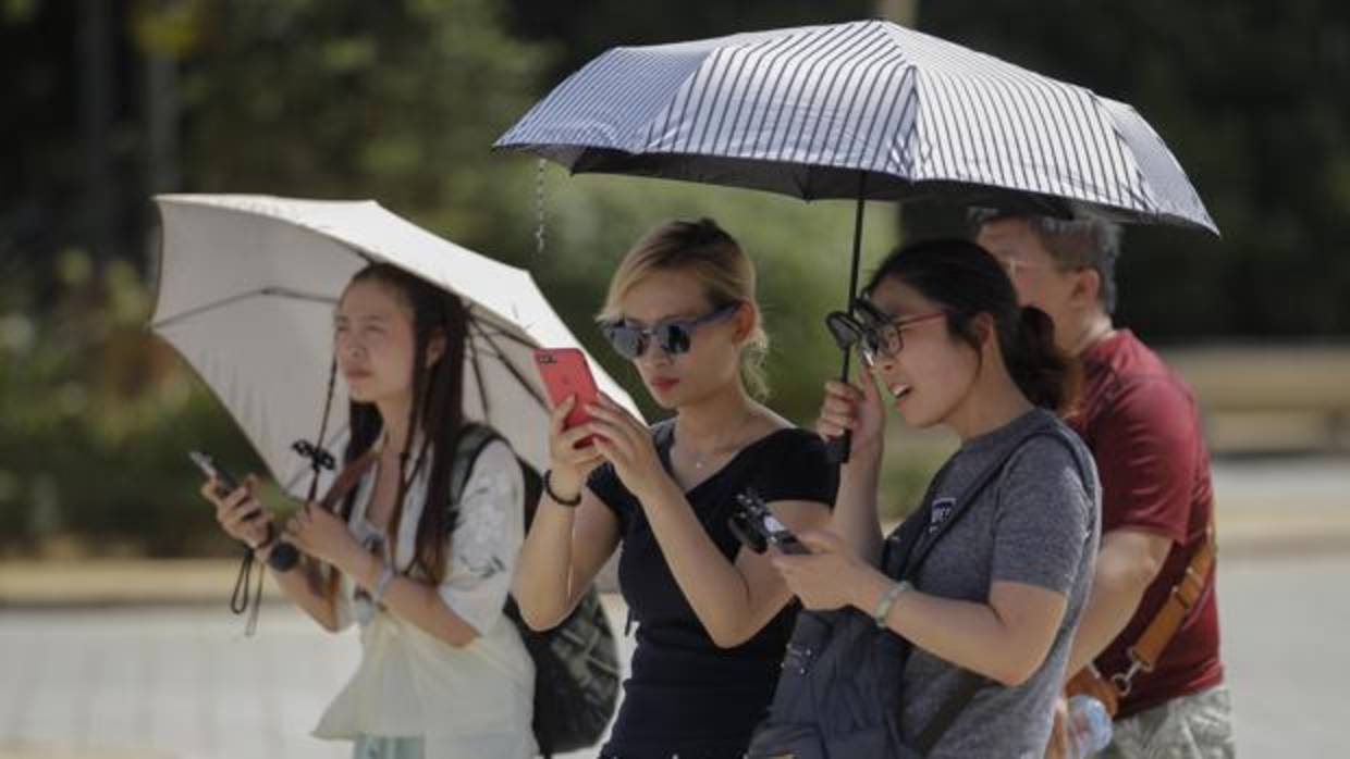 Unos turistas se protegen del calor con varios paraguas