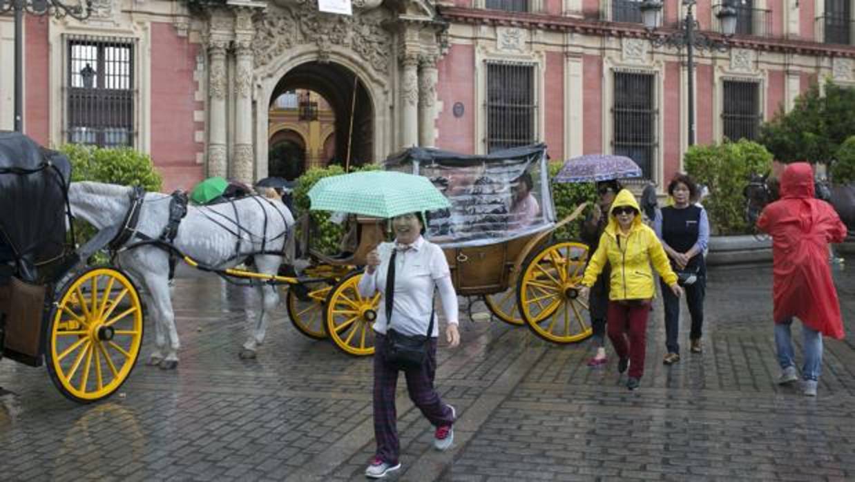 Turistas por el centro de Sevilla bajo la lluvia