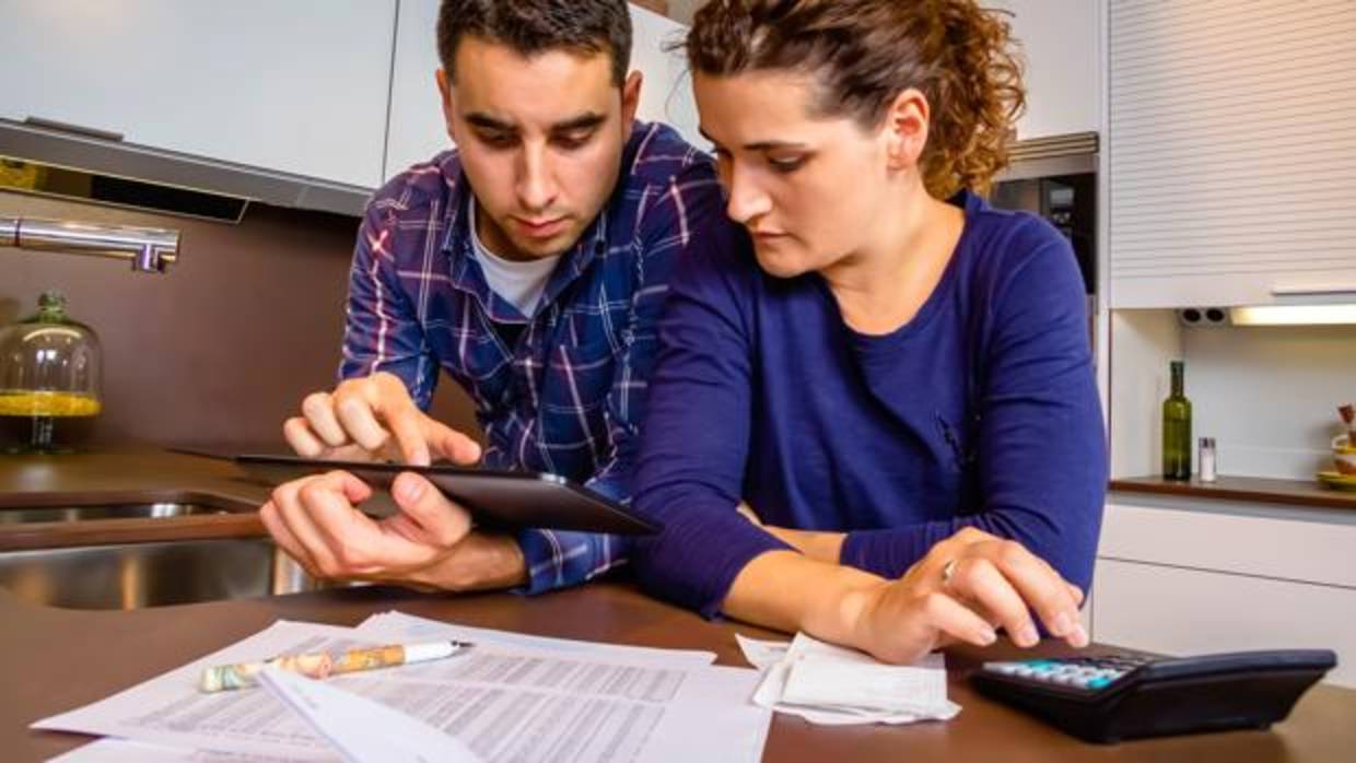 Una pareja con calculadora en mano en la cocina de su vivienda