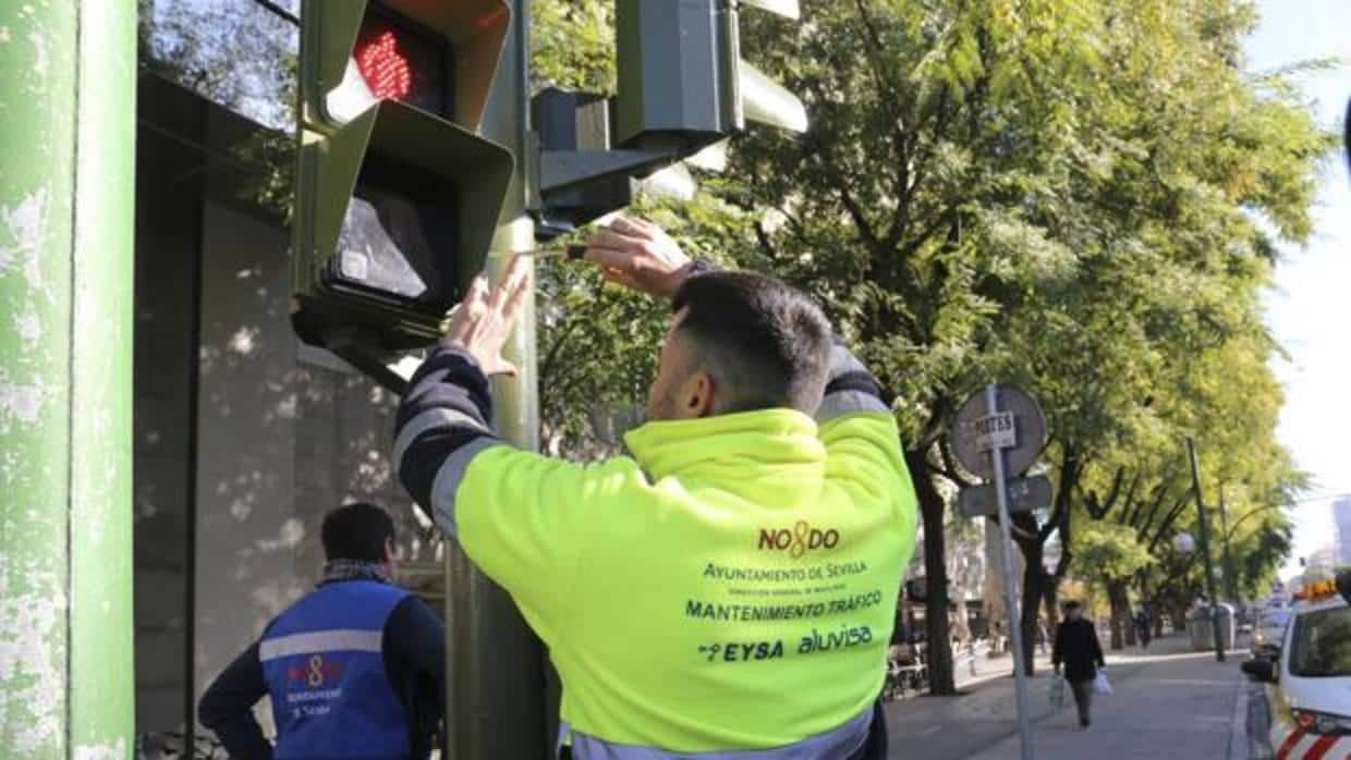 Un operario instala un semáforo para ciegos en el centro de Sevilla