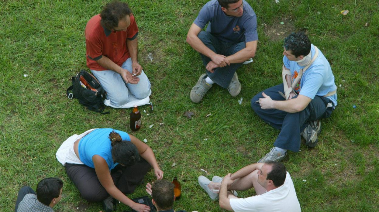 Un grupo de jóvenes fuman porros y beben alcohol en un parque