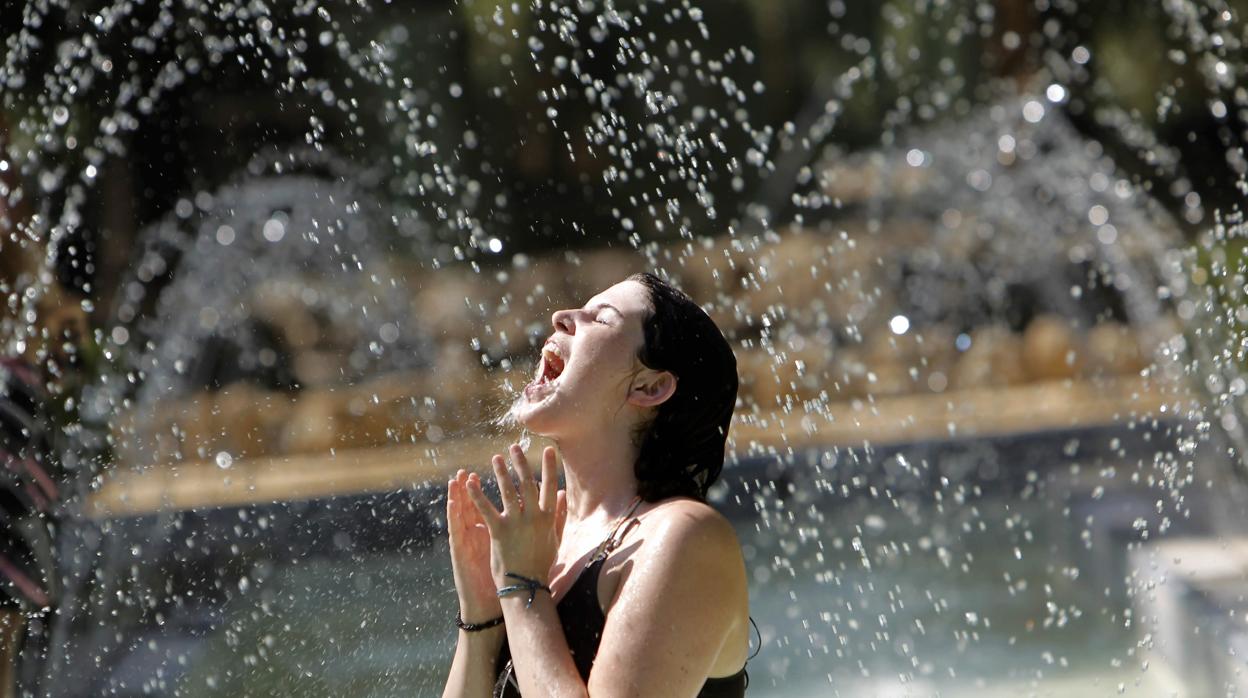 Una joven se regresca del calor en una fuente de Sevilla