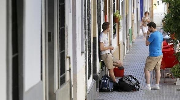 Unos turistas con sus maletas en una calle sevillana