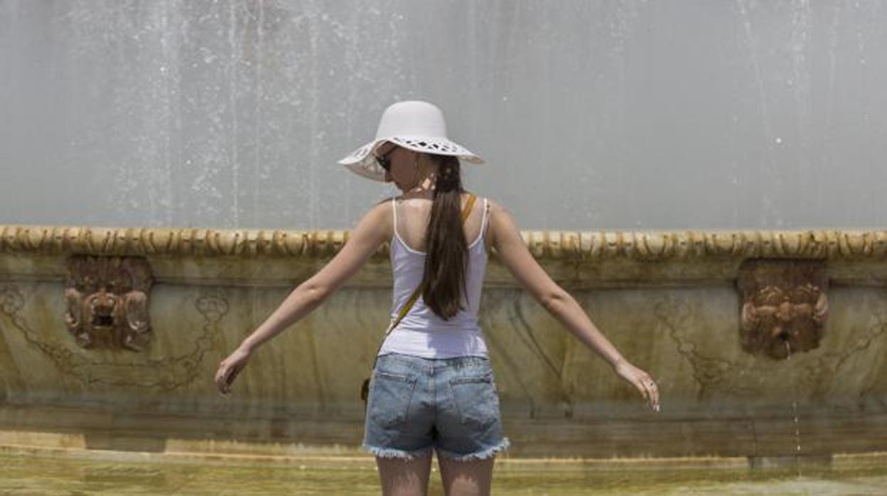 Una joven se refresca en una fuente de Sevilla