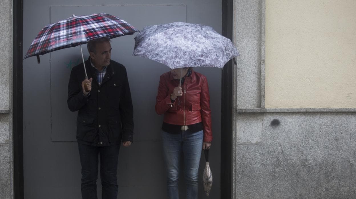Una pareja de viandantes se protege de la lluvia con unos paraguas