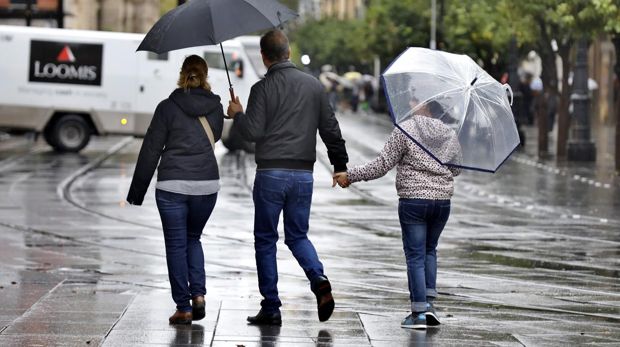 Una familia pasea por Sevilla en un día de lluvia