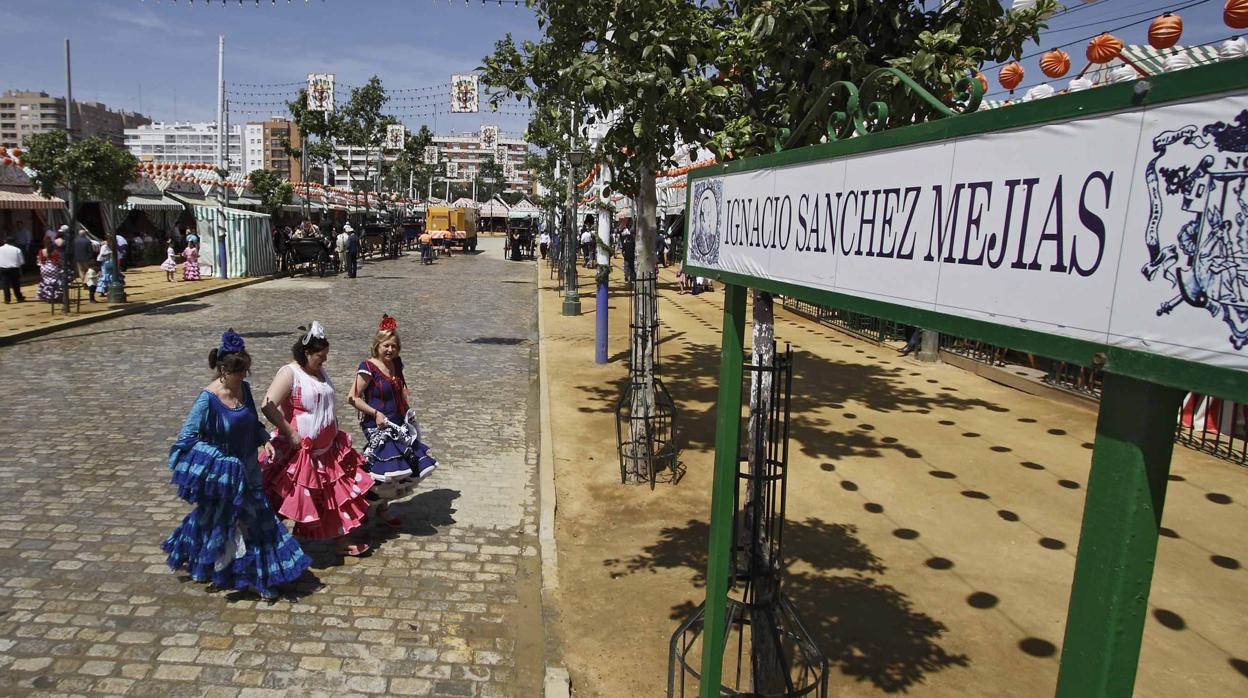 Mujeres vestidas de flamenca atraviesan la calle Sánchez Mejías
