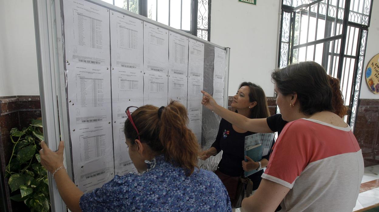 Varias mujeres consultan las listadde admitidos en un colegio