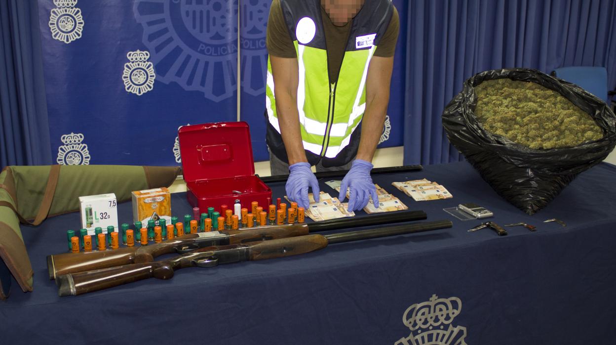Un agente muestra las armas y la droga incautada durante la operación policial