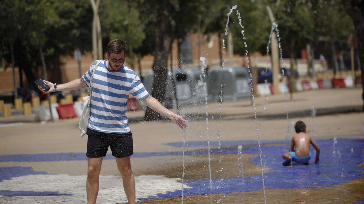 Un hombre se refresca en una fuente de la Alameda de Hércules