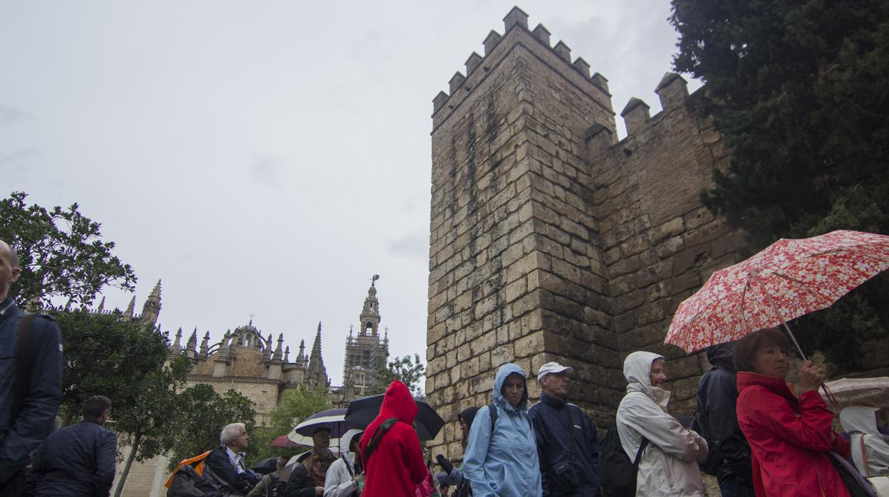 Varios turistas, bajo la lluvia en la cola para visitar el Alcázar de Sevilla