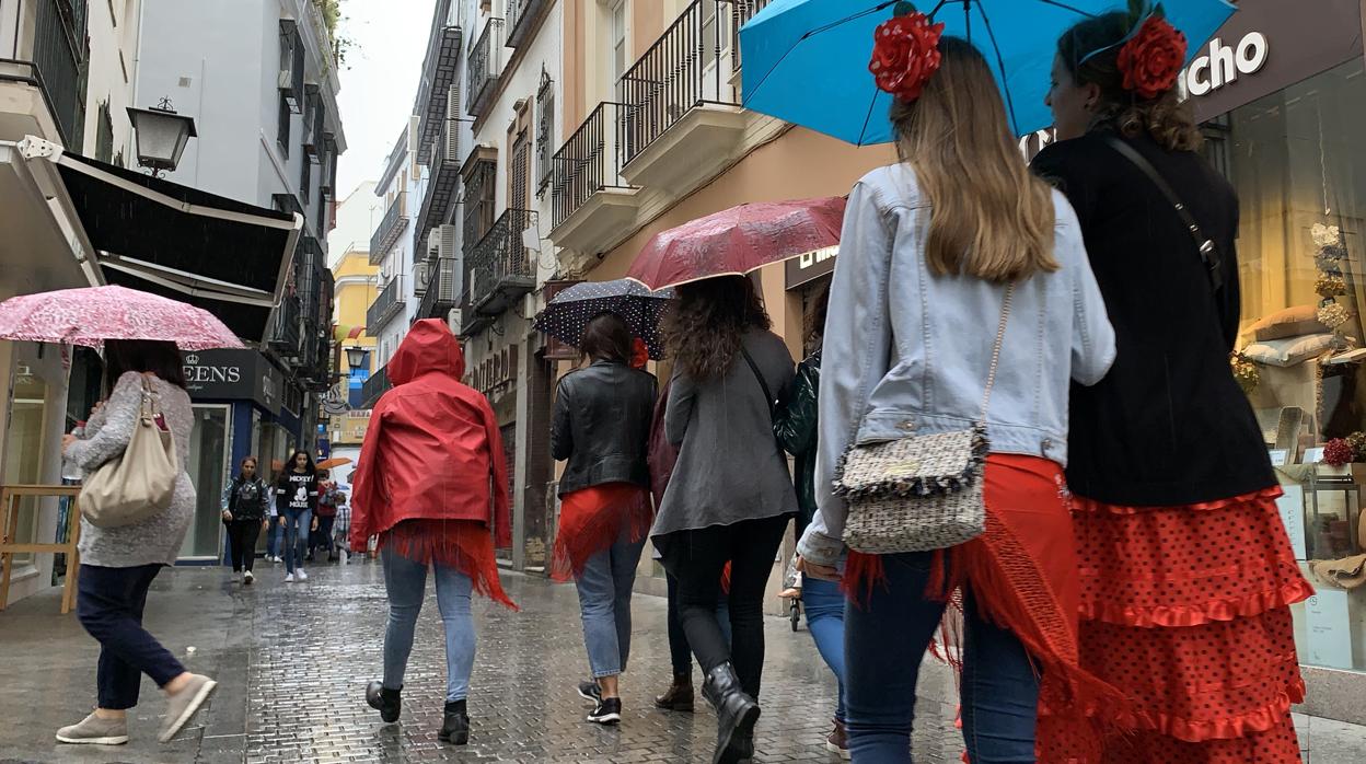 Un grupo de personas se resguardan de la lluvia por las calles de Sevilla