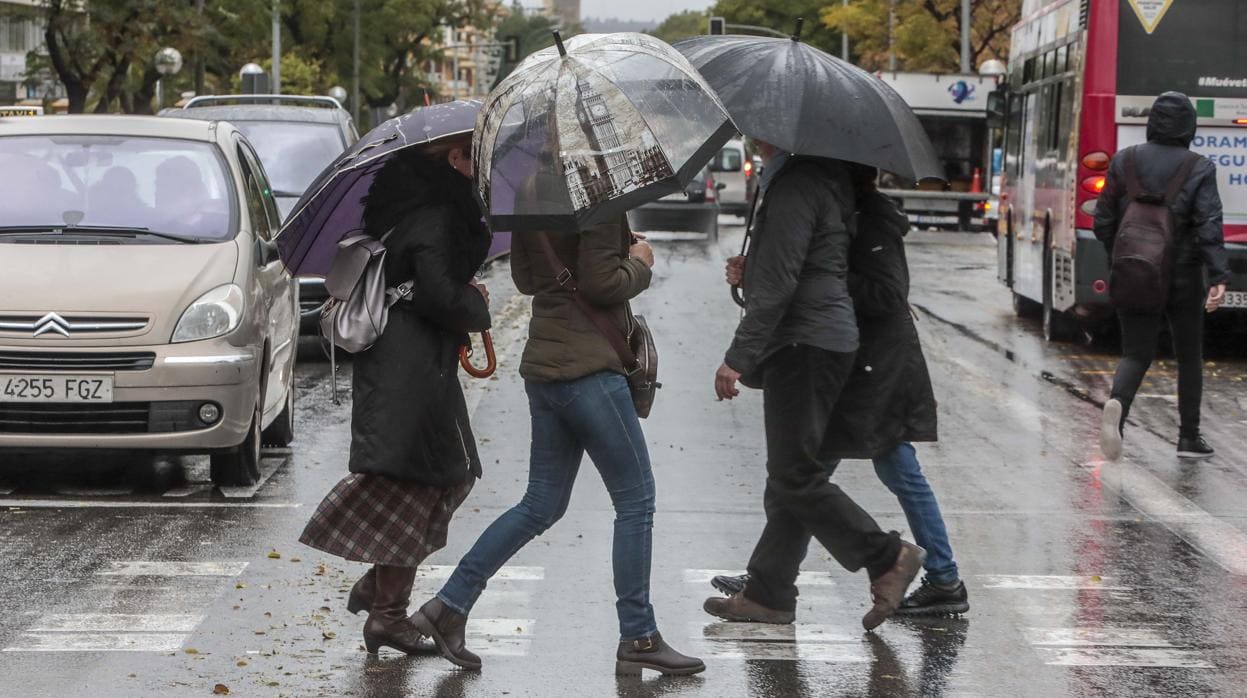Un grupo de personas se resguardan de la lluvia y el viento en Sevilla