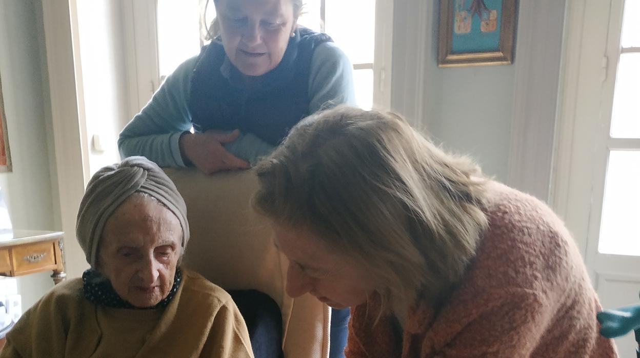 A sus 101 años, Pilar Mencos explica a sus sobrinas cómo se realiza una técnica de pintura sobre cristal