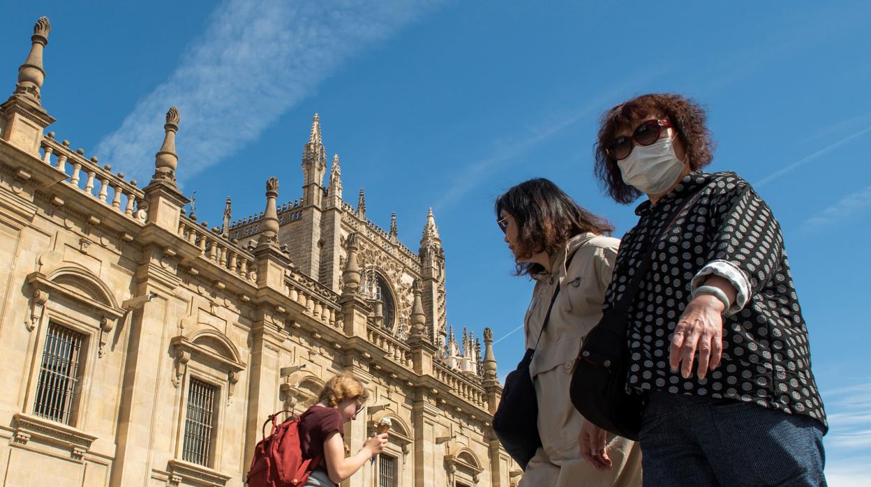 Dos turistas con mascarilla ante la Catedral de Sevilla