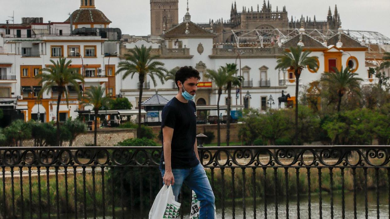 Un hombre por el puente de Triana tras hacer su compra