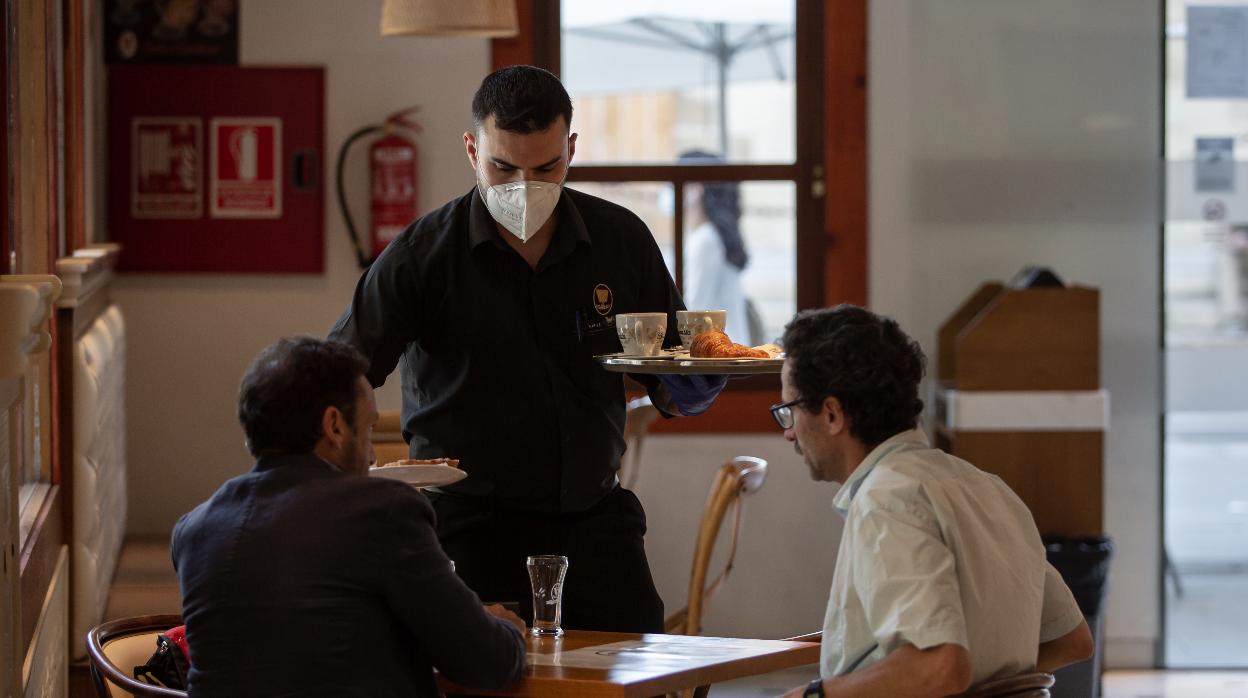 Un trabajador atiende una mesa en un restaurante de Sevilla