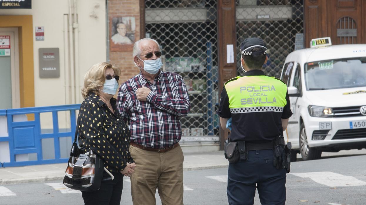 Dos viandantes reciben explicaciones de un agente de la Policía Local de Sevilla en Triana