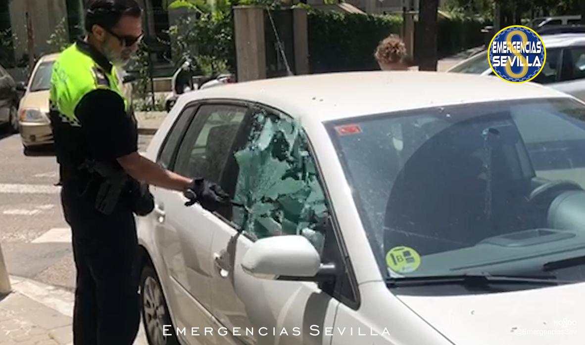 El agente procede a romper una de las ventanillas del vehículo