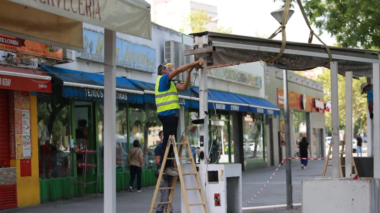 Un operario de Urbanismo, ayer en Pino Montano cortando con una radial la estructura de toldos de un bar