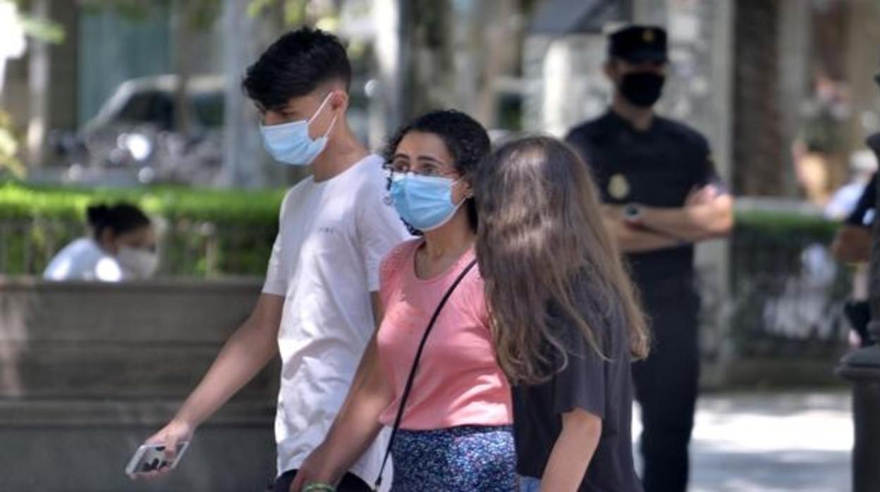 Tres personas pasean por Sevilla con mascarilla