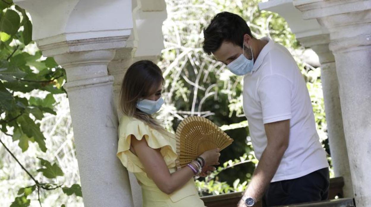 Dos jóvenes con mascarilla en el Parque de María Luisa.