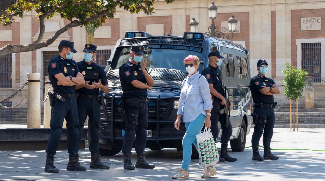 Una mujer pasea por el Centro Histórico de Sevilla junto a unos policías