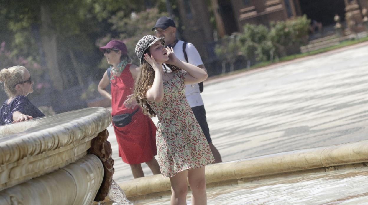 Una joven se refresca en la Plaza de España de Sevilla