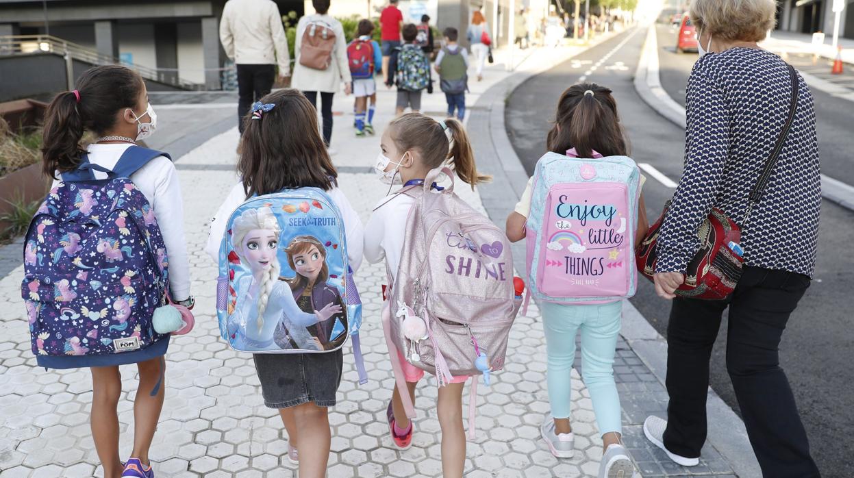 Varias niñas con mascarillas camino del colegio