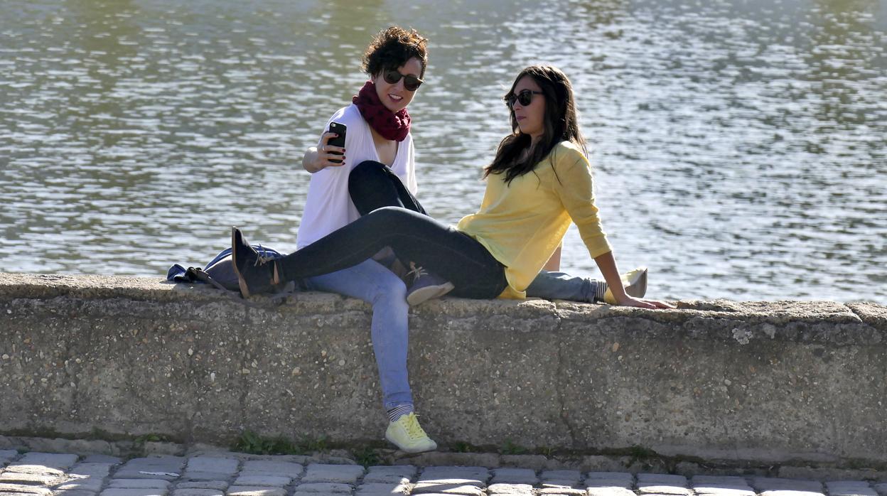 Dos jóvenes se hacen un selfie junto al río Guadalquivir