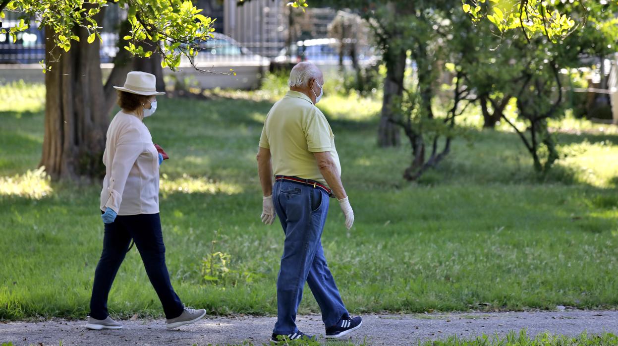 Dos personas pasean por el Parque de los Príncipes de Sevilla